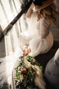 bride dressed in a flowy wedding dress, posing alongside her flower bouquet